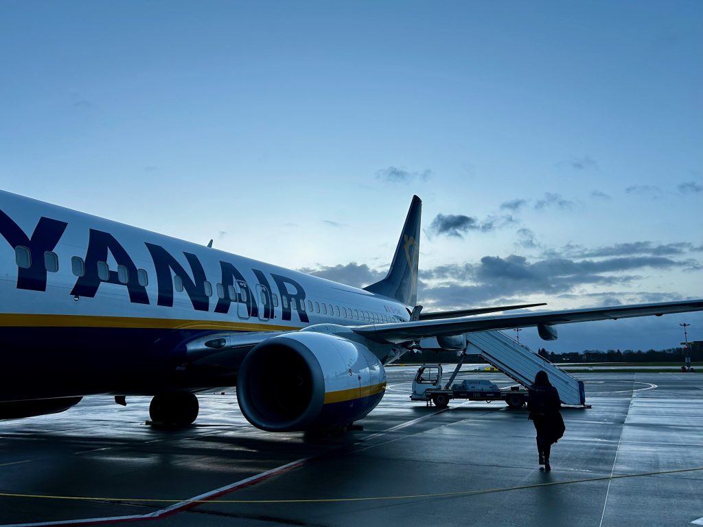 A lone traveller walking towards an aircraft on the tarmac at dusk.